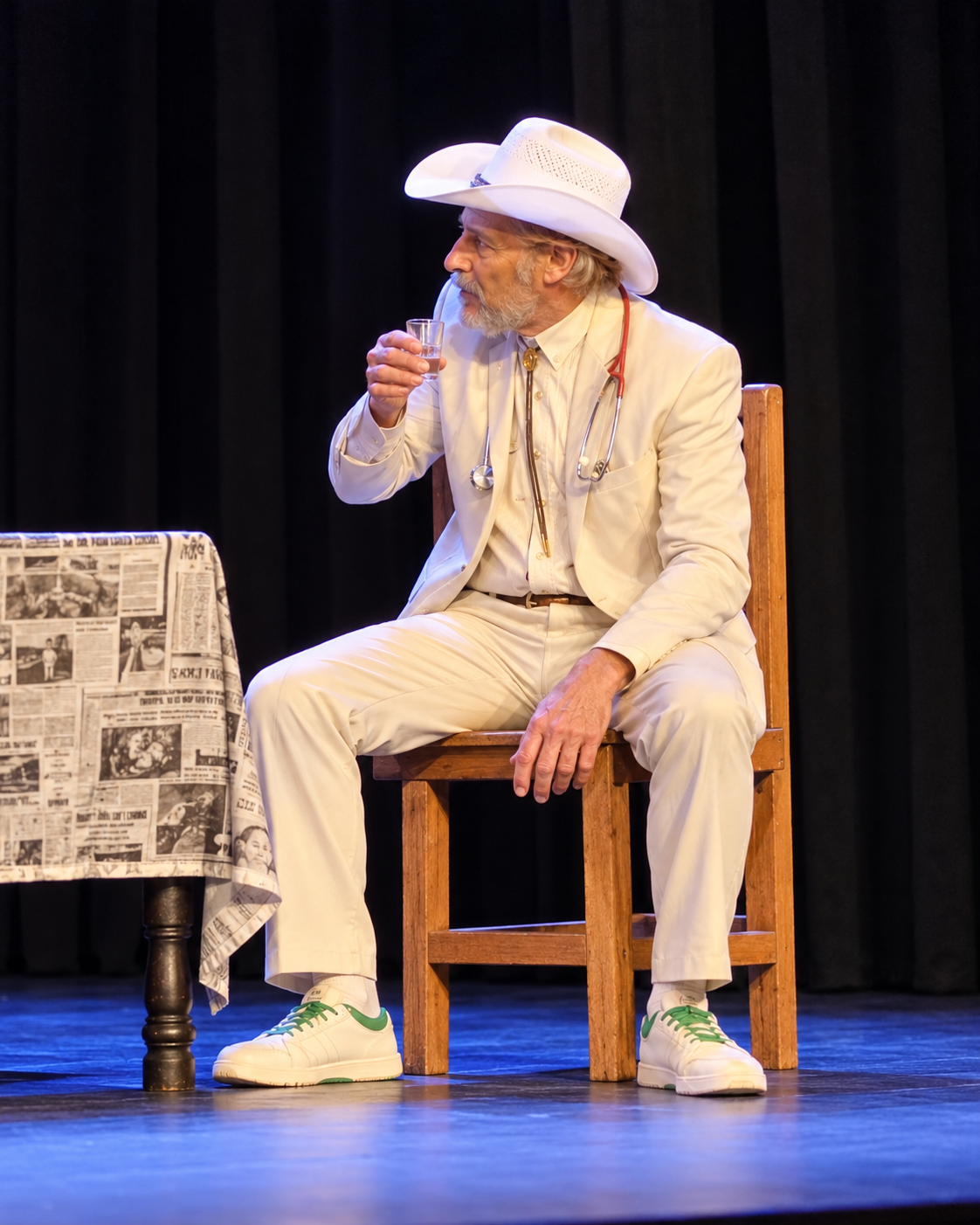 Andrew performing on stage in a white suit and cowboy hat